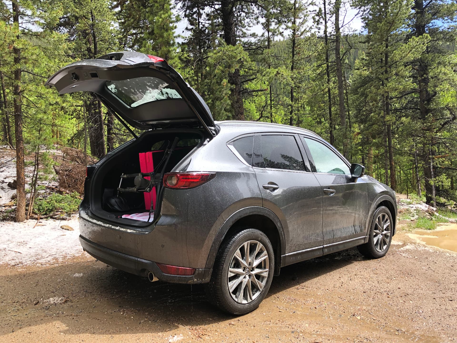 Mazda parked at a forest trailhead with the hatch open