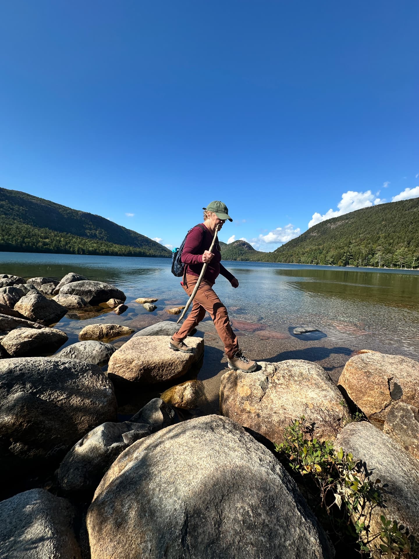 Emily stepping across rocks beside Jordan Pond in Acadia